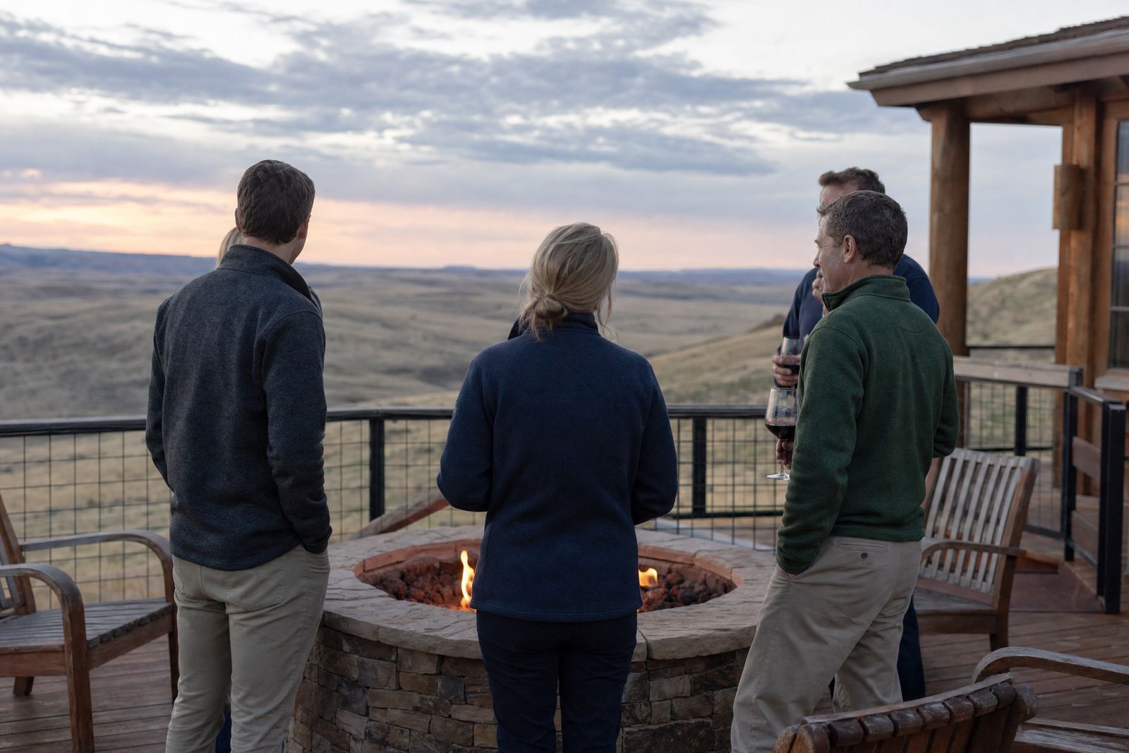 Small group around a fire pit on a lodge deck at dusk