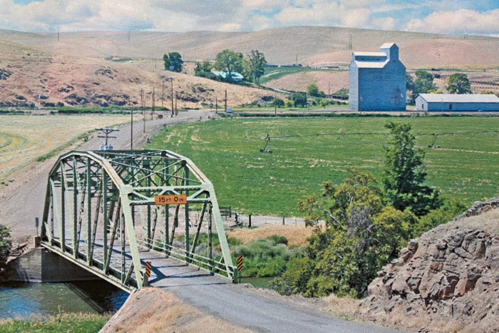 Truss bridge over the river and the grain elevator on the valley floor